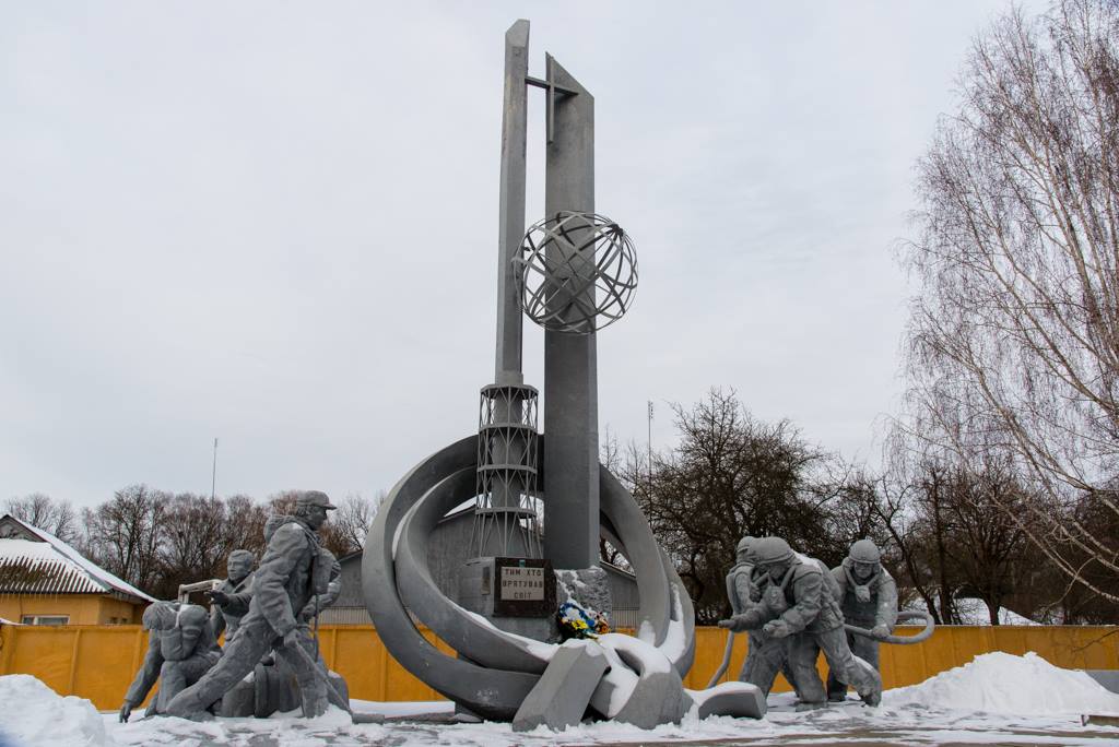 Image of a monument constructed to commemorate the firefighters that lost their lives during the Chernobyl disaster. The image shows stone firefighters carrying hoses. 