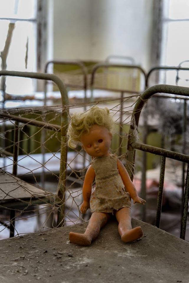 Eerie photo of a dirty doll, missing an eye, sitting on one of the abandoned bunk beds at the Kopachi Kindergarten. 