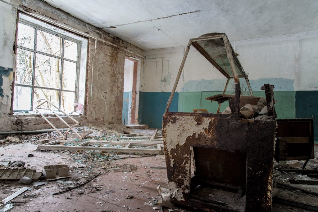 Photo of an abandoned supermarket. All shelves and food has been removed, however the old fashioned fridges remain. 