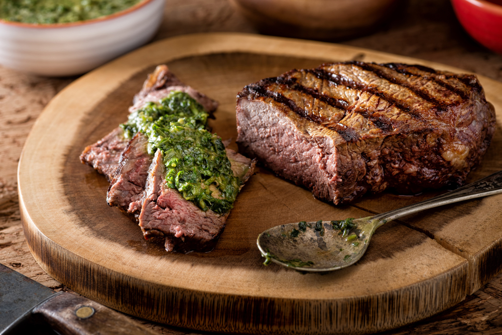 Photo of a large piece of beef with chimichurri sauce on it