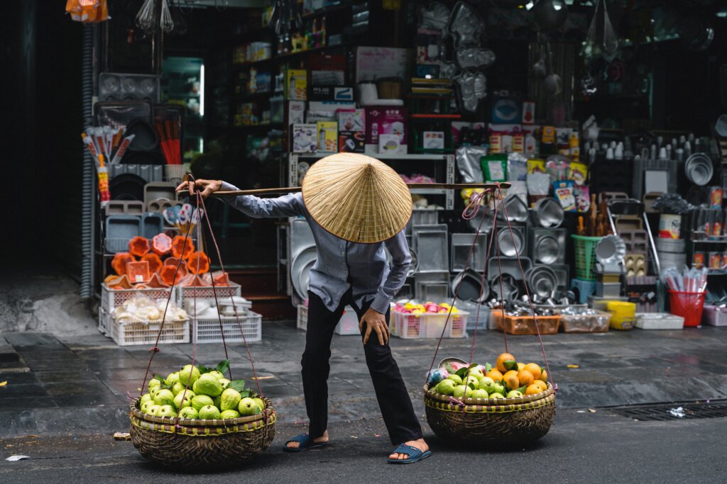 A free Hanoi attraction is wondering the streets of Hanoi Old Quarter admiring how the fruit sellers precariously balance the fruit in two baskets 