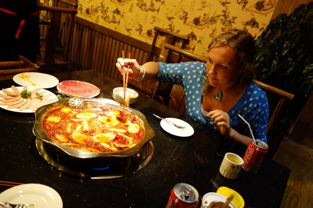 Photo of the hot pot with the meat on the side and me putting some food in it. 