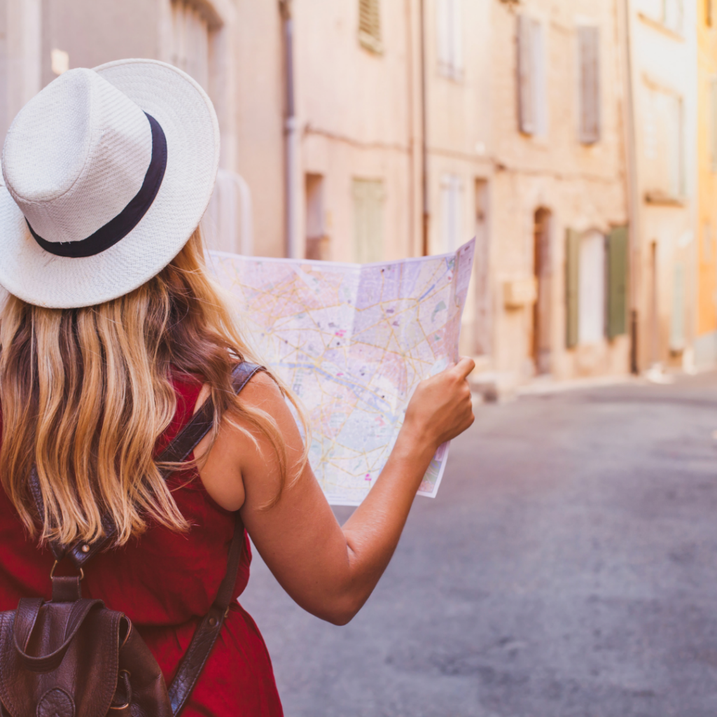 Photo of a girl with a hat on looking at a map, very obviously a tourist and not blending in as a local
