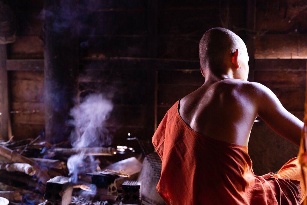 Photo of a monk we met whilst in Cambodia cooking over an open fire inside their wooden hut