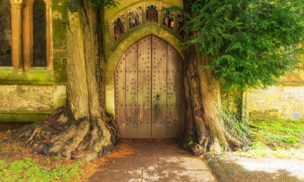 St Edwards church door lined by two large trees, One of the top places to visit in North Cotswolds