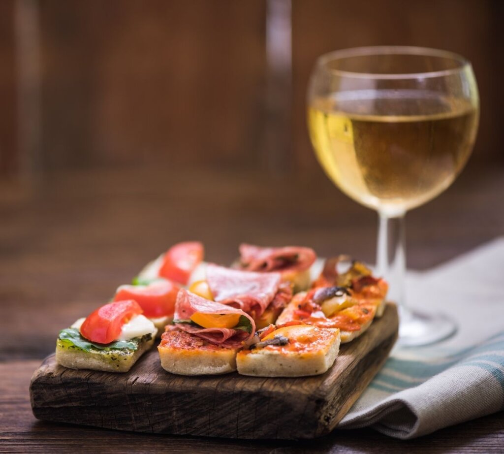 Photo of a glass of wine with a plate of tapas