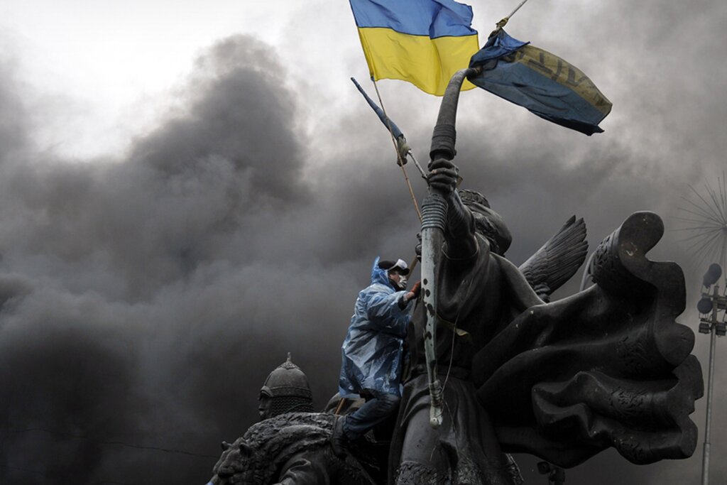 Photo of a protester flying the Ukrainian flag in Kiev under a dark moody sky