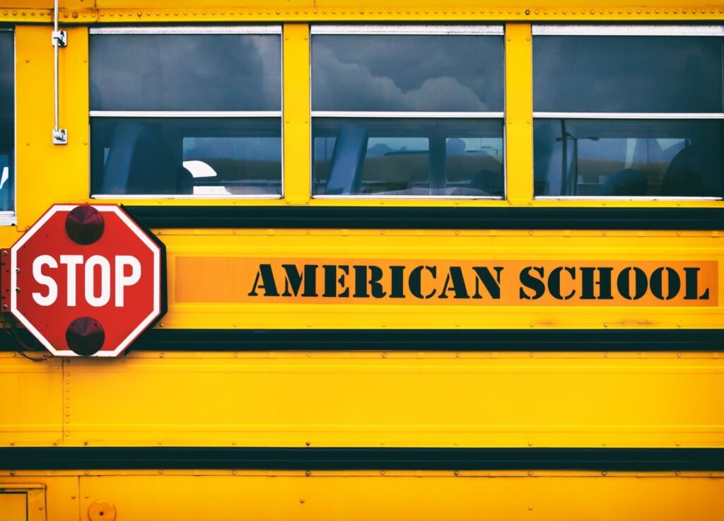 An American yellow school bus with the red stop sign that gets flipped when the bus stops at a bus stop