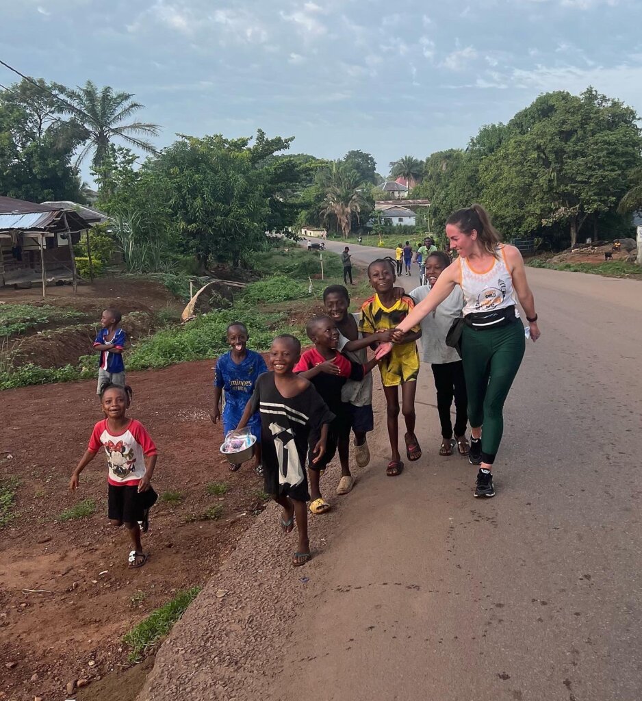 One of the Sierra Leone half marathon runners, Bianca running alongside 8 children, all keen to hold her hand