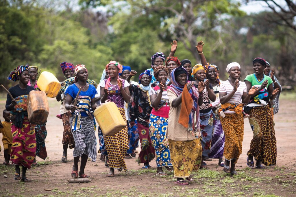 A group of women cheering, singing and dancing wearing their colourful outfits