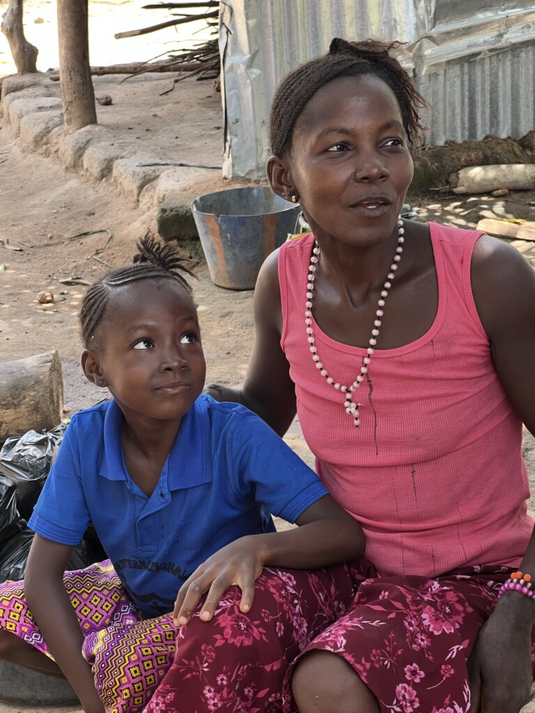 A mother with an amputated hand sitting next to her young daughter who looks up at her with admiration. Another beneficiery of the marathon