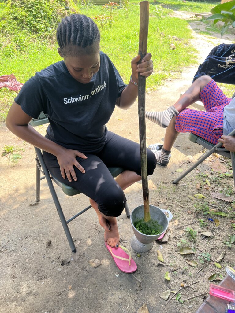 Our cook grinding the cassava leaf with a mortar and pestle, only the pestle is a long stick!  