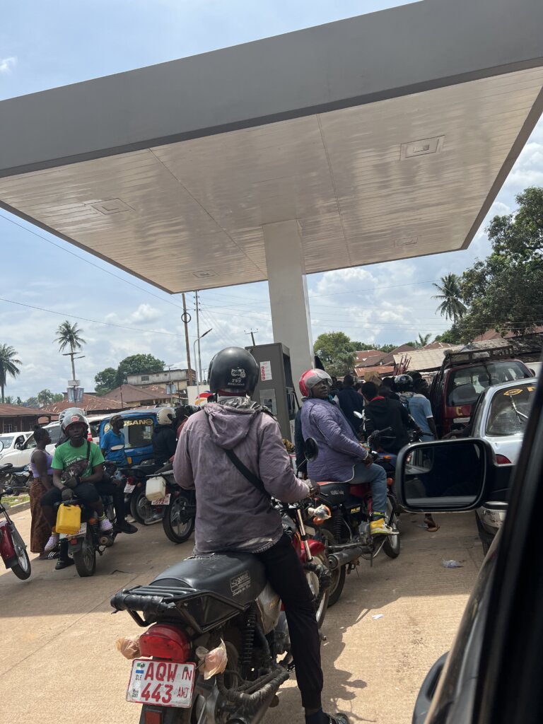 A long queue of bikes, cars and people are gathered around the petrol pump waiting for the green light for dispensing to start again during the Sierra Leon gas crisis