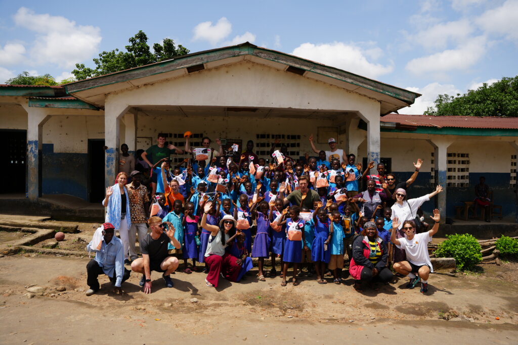 All the kids standing outside the school waving at the camera