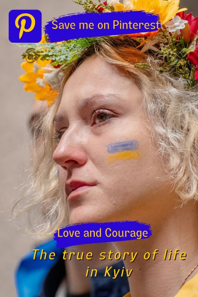 A girl with sad eyes and flowers on her head, has the Ukrainian flag painted on her cheek. It's the pin to encourage people to save the post for later