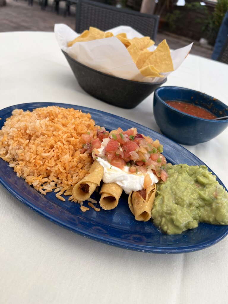 A delicious place of rice, flautas, sour cream, pico de gallo and guacamole