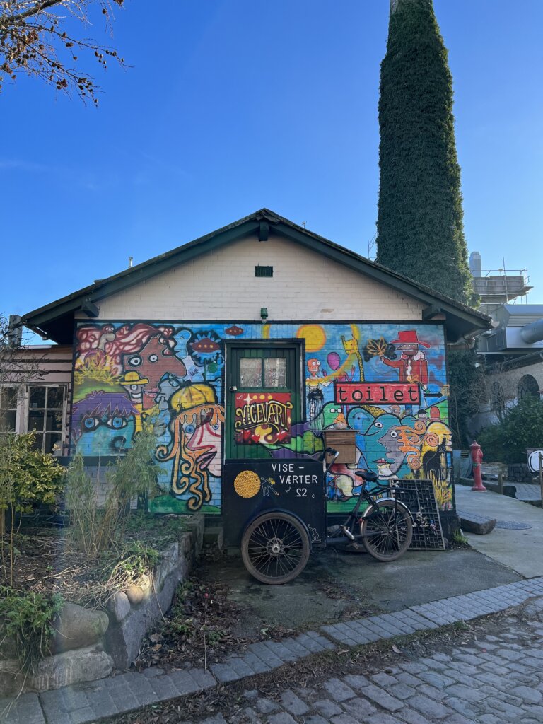 A colourful building with the sign toilet and a bike parked outside