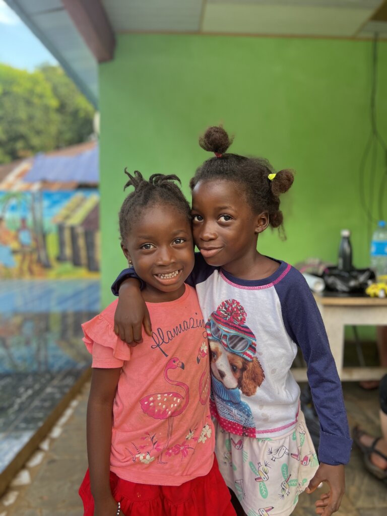 Two lovely young girls hug each other as they pose for the camera