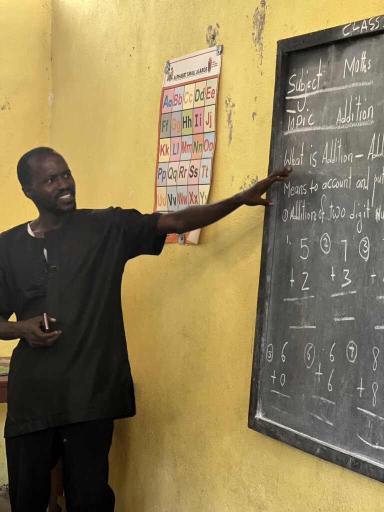 A teacher points at the blackboard