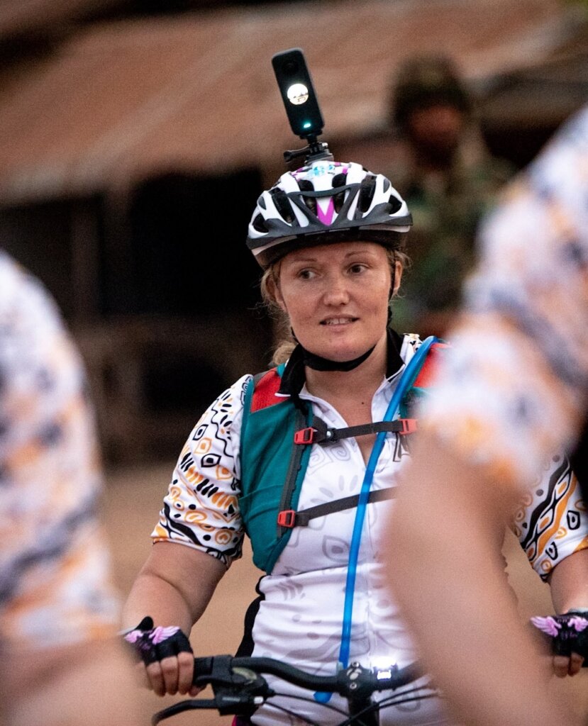 Bea in her bike gear, framed between two arms, everyone sporting the Street Child Bike vests