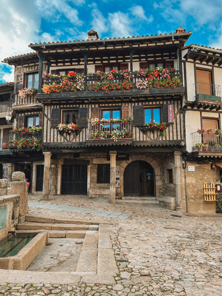 A colourful old timber home dressed in spring flowers in the central square of La Alberca