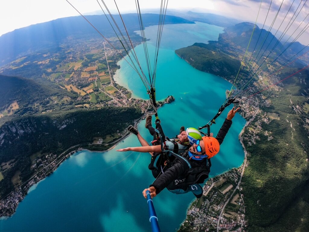 Paragliding over the bright blue waters of Lake Annecy in the summer