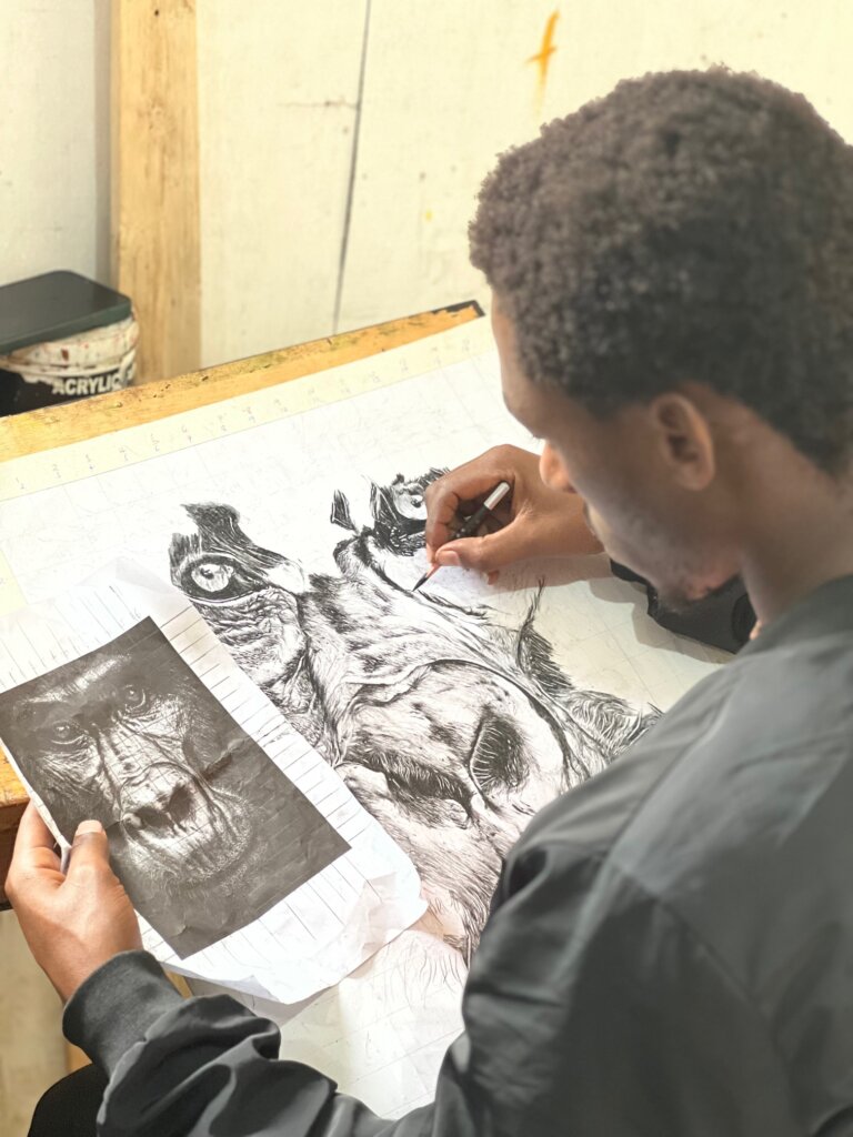 Deus working on a charcoal painting of a gorilla