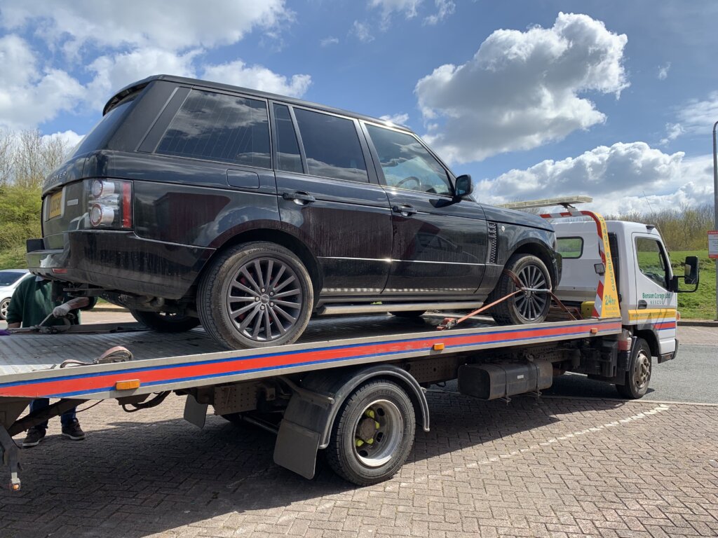 A broken down Range Rover on the back of a recovery van