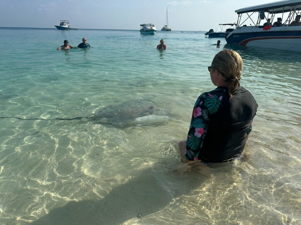 Bea kneeling in the water with a manta ray just in front