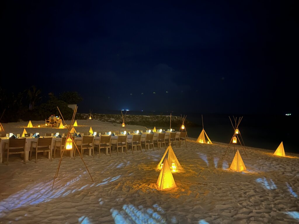 Long table laid out on the beach with candles