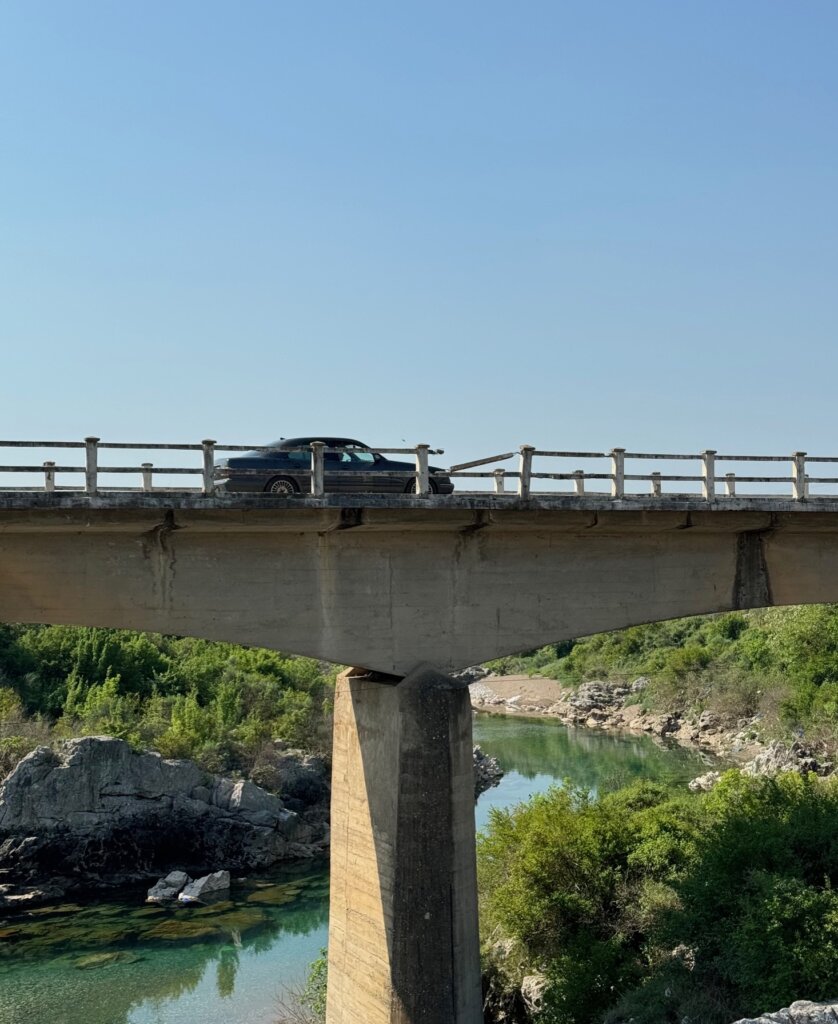 A bridge with a car driving over and a broken rail