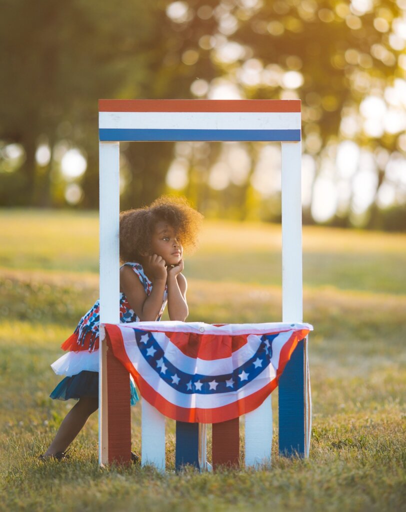 Little girl sitting at a booth with the American flag