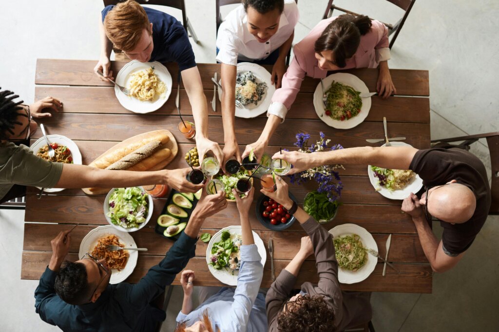 A group of people cheering over a table full of food