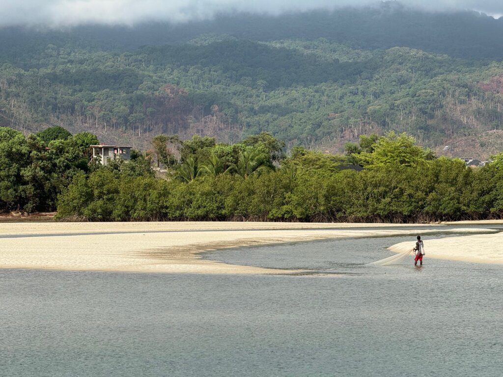 My favourite beach in Sierra Leone, River No 2 Beach, with a fisher man standing in the shallow waters