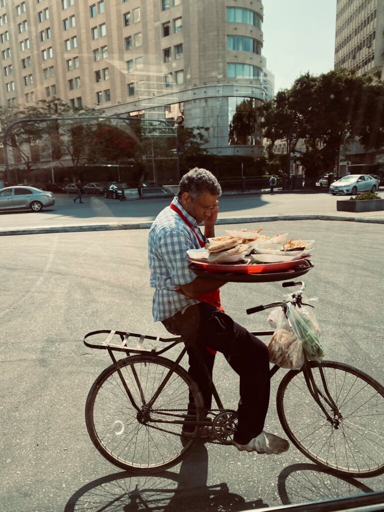 man on a bicycle holding a tray with food