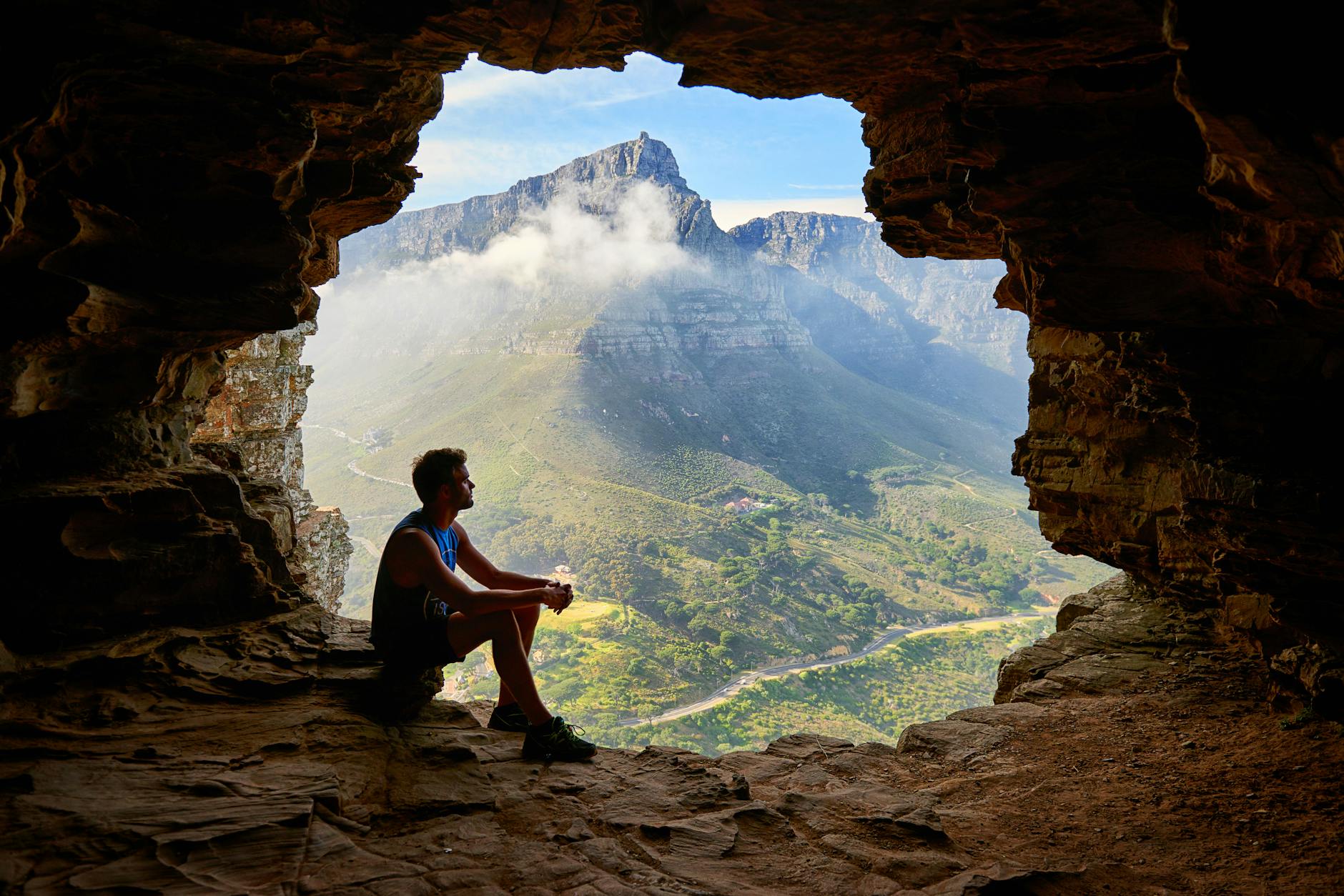 photo of man sitting on a cave