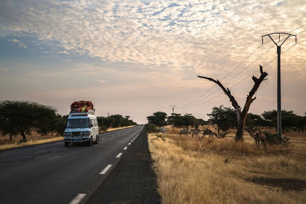 Alt text: Loaded van on African savanna road.