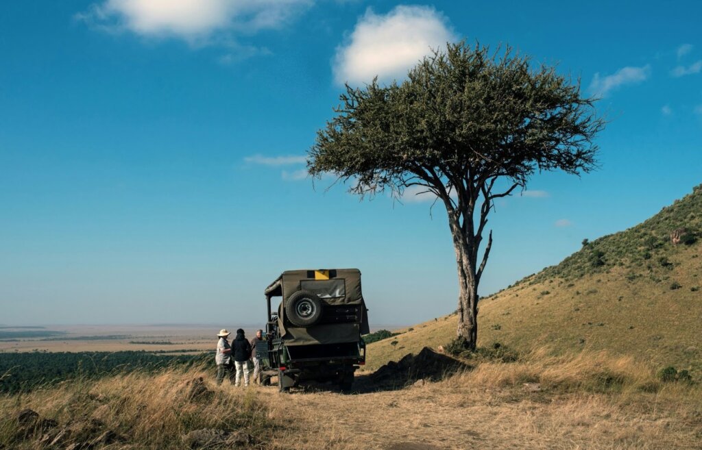 Alt text: Safari truck parked under acacia tree.