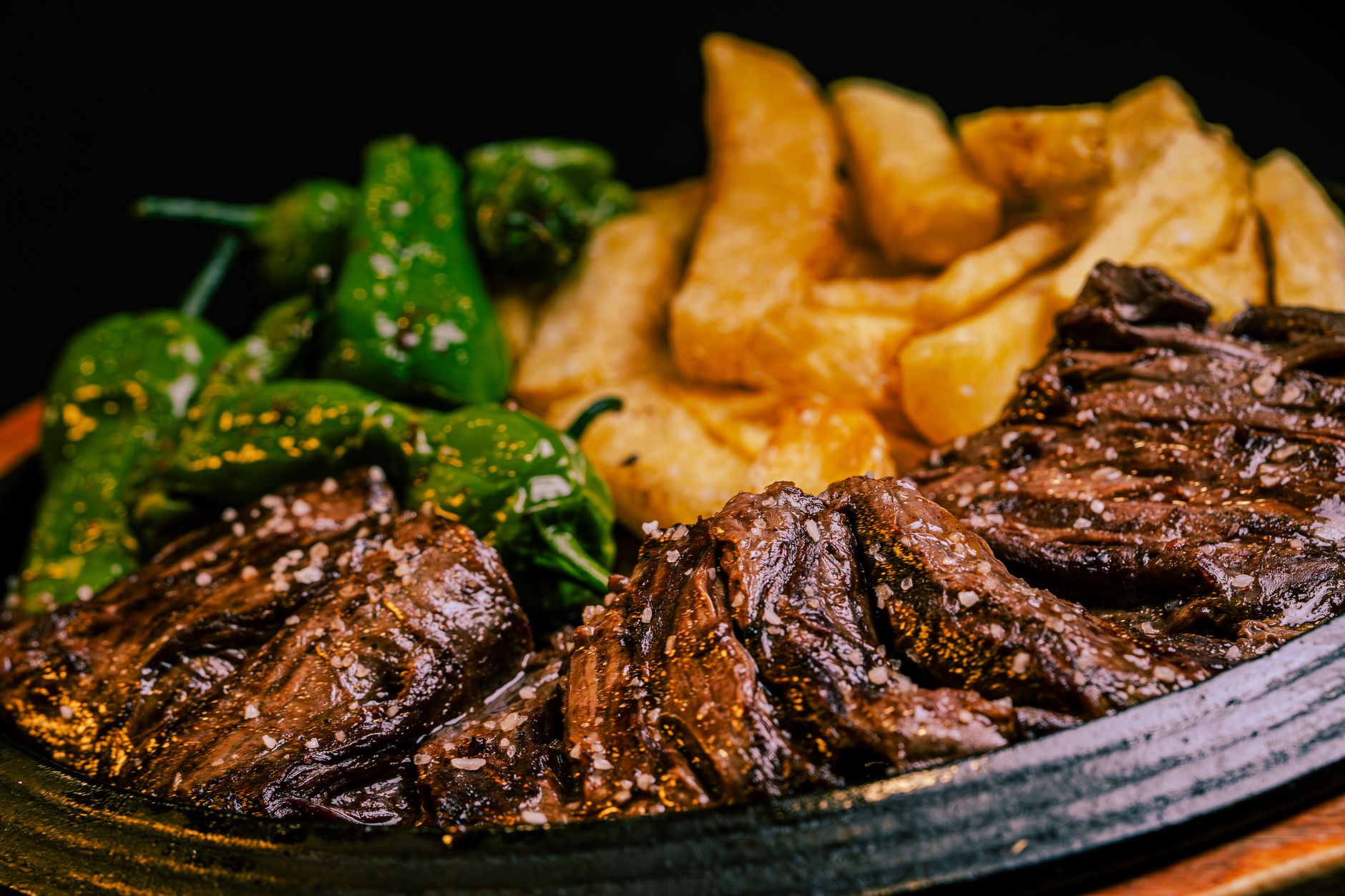 a plate of steak and potatoes with green peppers